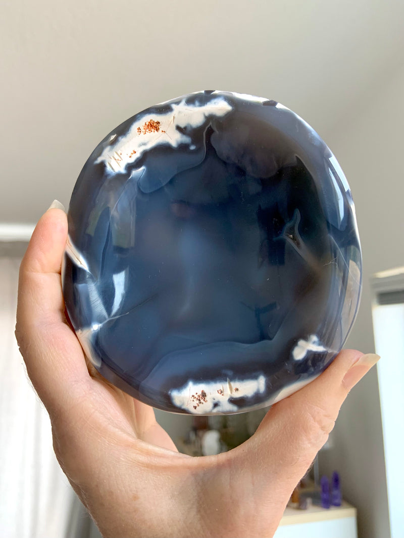 Orca Agate Offering Bowl held up in natural light show the inky blue gray colors and translucence in the natural stone