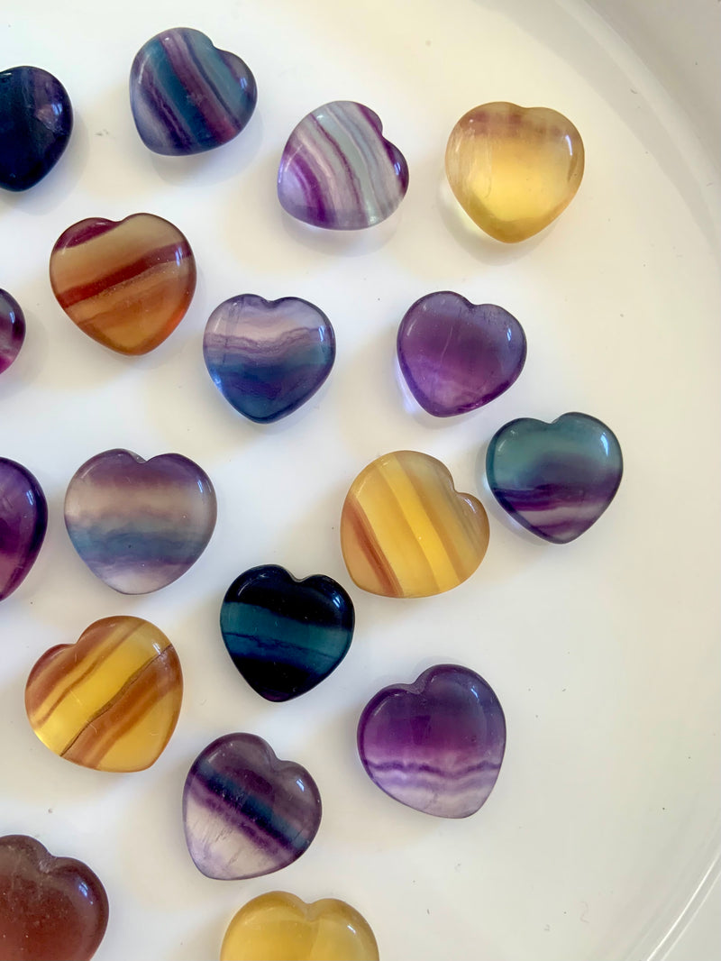 Small Rainbow Fluorite Hearts in a variety of colors including purple, blue magenta, teal, and yellow. Mini crystal heart, banded candy fluorite pocket stones make a sweet little gift + addition to your crystal collection