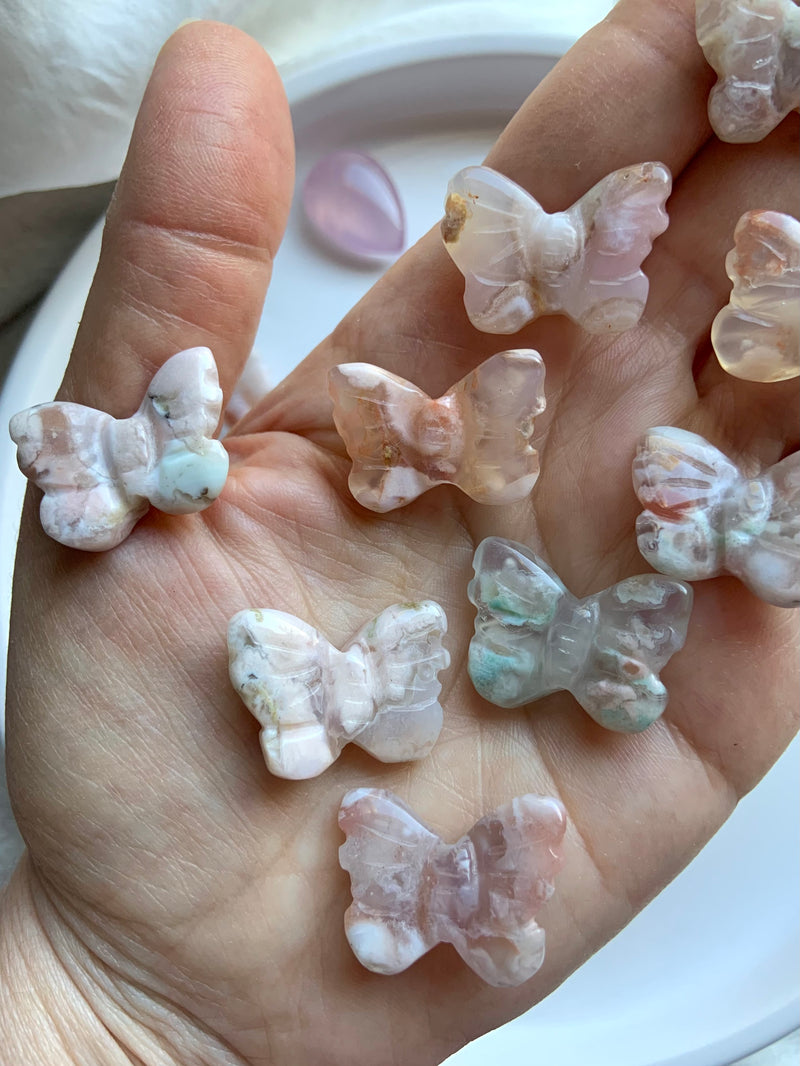 An closeup of the Mini pastel Flower Agate Butterfly Carvings shown on my hand for scale