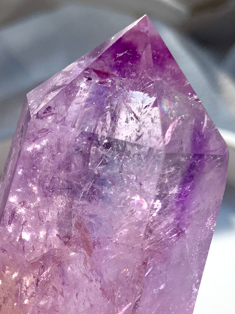 A closeup pic of a Smokey Amethyst Point with Golden Healer and rainbows, polished amethyst crystal